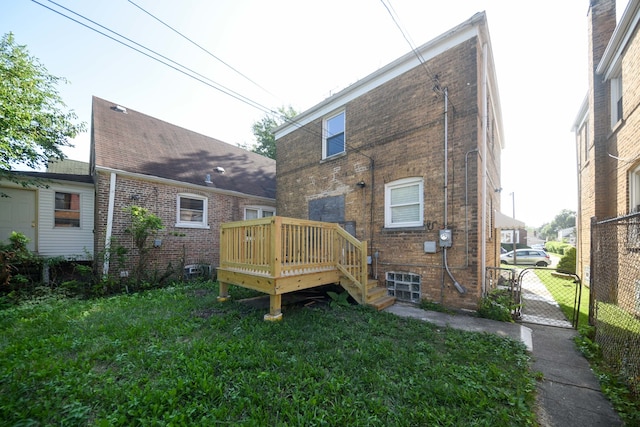 rear view of property featuring a wooden deck and a lawn