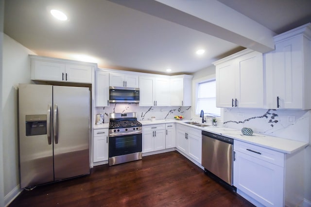 kitchen with tasteful backsplash, appliances with stainless steel finishes, sink, white cabinetry, and dark wood-type flooring