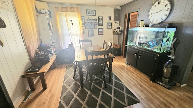 dining area with hardwood / wood-style flooring and wooden walls