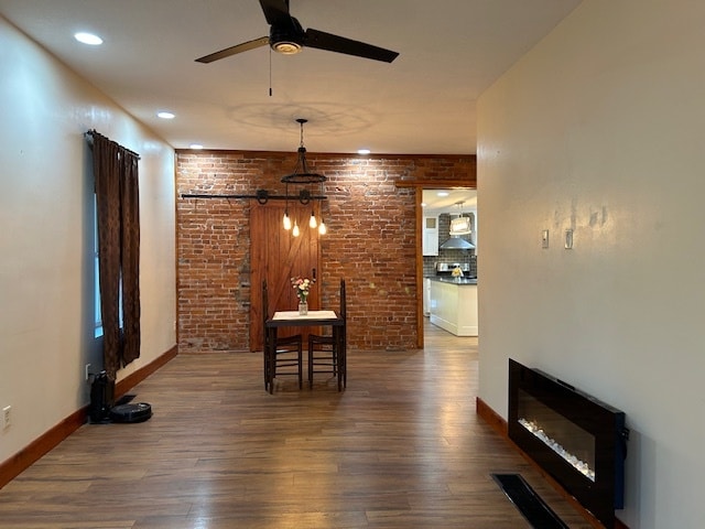 dining room featuring brick wall, a fireplace, and wood-type flooring