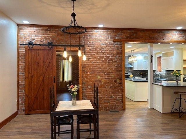 dining room featuring brick wall, sink, a barn door, and hardwood / wood-style floors