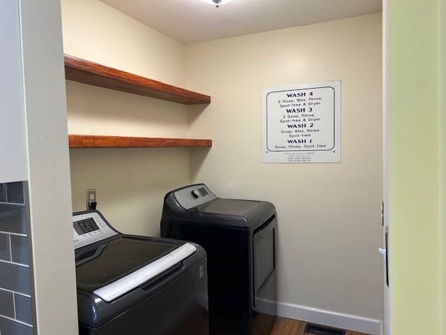 clothes washing area featuring washing machine and clothes dryer and hardwood / wood-style flooring