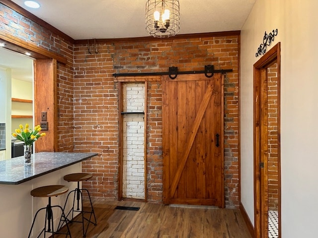 entryway with hardwood / wood-style flooring, a barn door, and brick wall