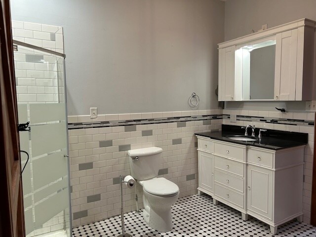 bathroom featuring vanity, toilet, tile walls, and an enclosed shower