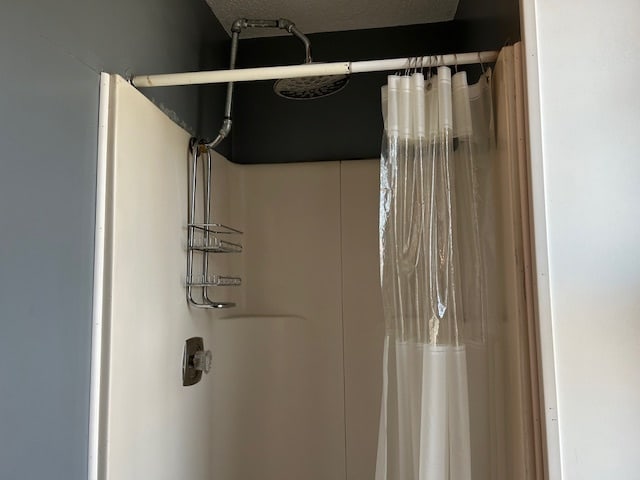 bathroom with curtained shower and a textured ceiling