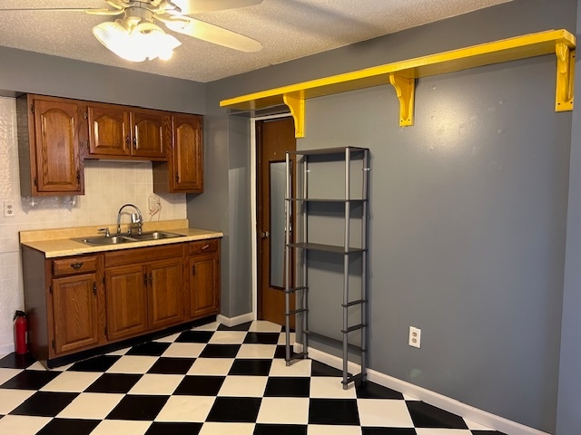 kitchen with a textured ceiling, sink, and ceiling fan