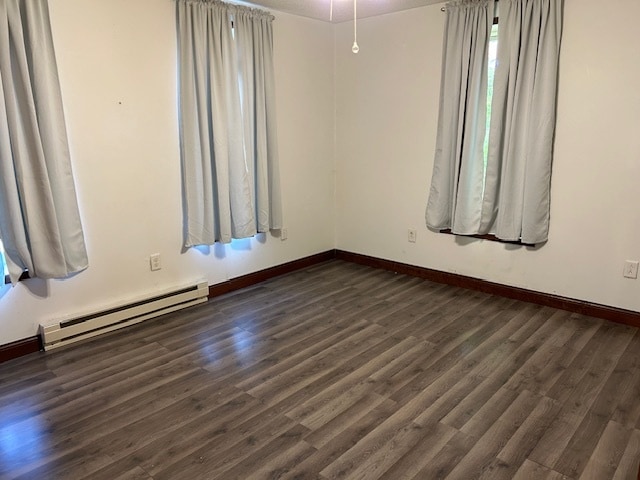 unfurnished room with a baseboard heating unit and dark hardwood / wood-style flooring