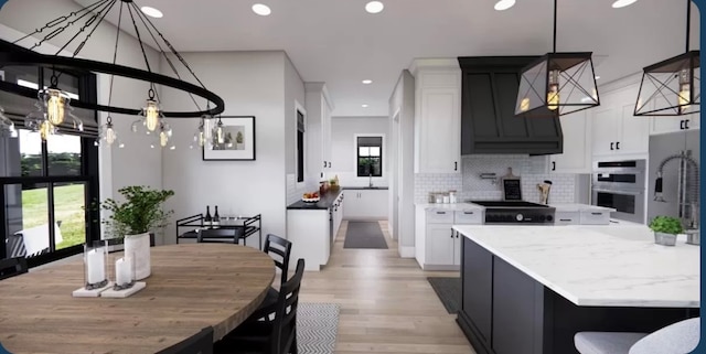 kitchen with double oven, white cabinets, light wood-type flooring, and tasteful backsplash