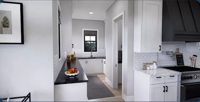 kitchen featuring stainless steel range with electric stovetop, decorative backsplash, white cabinetry, and light hardwood / wood-style floors