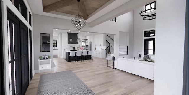 bathroom with an inviting chandelier, hardwood / wood-style flooring, beamed ceiling, and a high ceiling