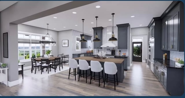 kitchen with a healthy amount of sunlight, wood counters, light wood-type flooring, and hanging light fixtures