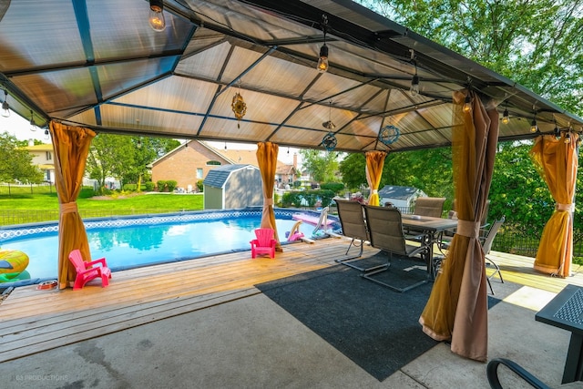 view of pool featuring a gazebo, a storage shed, a deck, and a yard