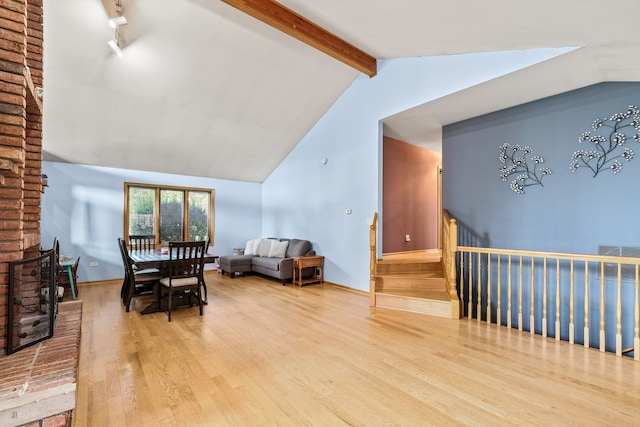 dining space featuring wood-type flooring and vaulted ceiling with beams