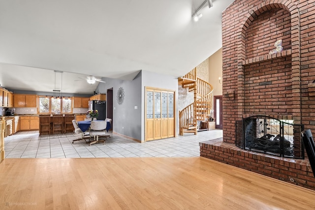 tiled living room featuring lofted ceiling, a fireplace, and ceiling fan