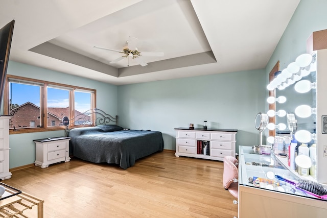 bedroom with light hardwood / wood-style floors, a raised ceiling, and ceiling fan