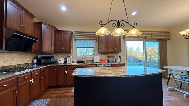 kitchen featuring a kitchen island, plenty of natural light, ventilation hood, and hanging light fixtures