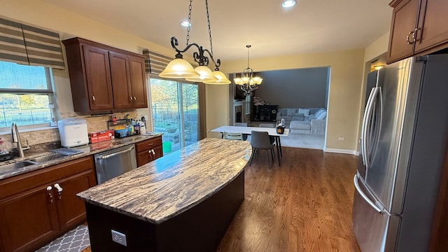 kitchen featuring appliances with stainless steel finishes, an inviting chandelier, a healthy amount of sunlight, and a center island