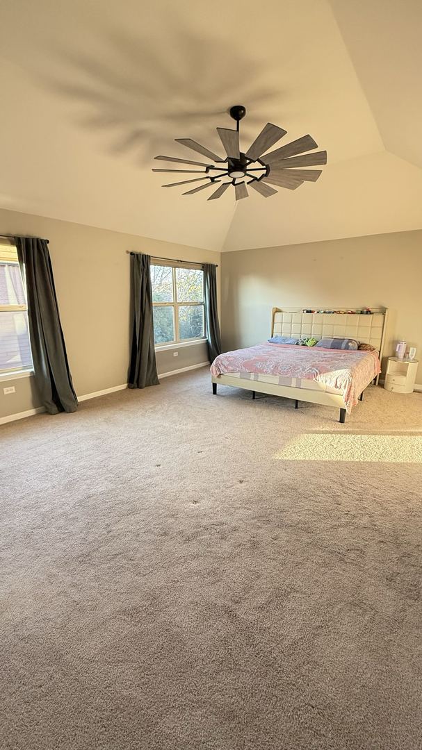 unfurnished bedroom with carpet flooring, vaulted ceiling, and ceiling fan