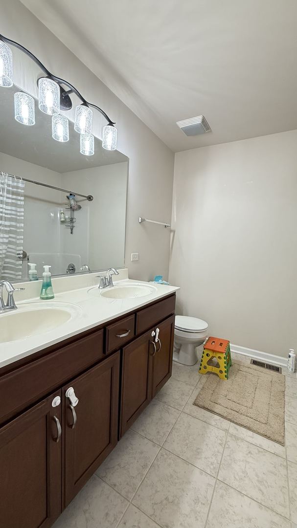 bathroom featuring toilet, walk in shower, vanity, and tile patterned floors