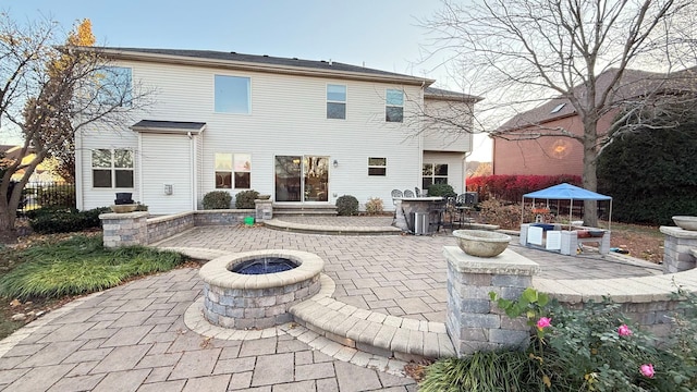 rear view of property with a patio and an outdoor fire pit