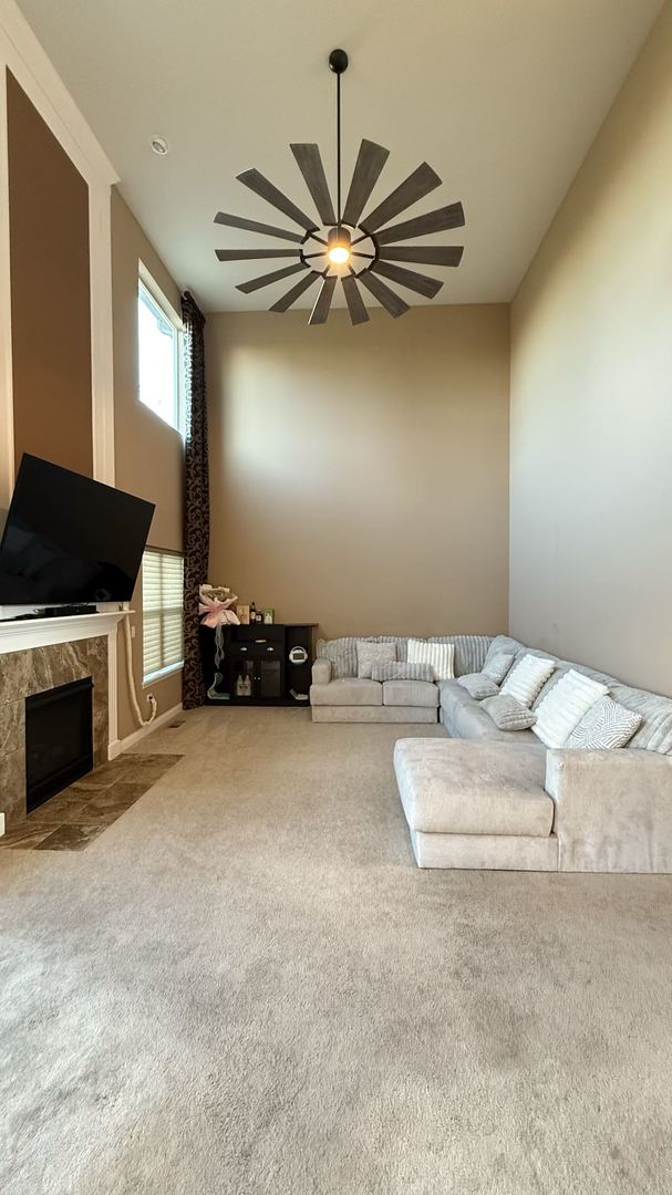 unfurnished living room with a fireplace, carpet floors, and ceiling fan