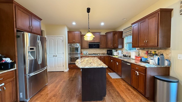 kitchen with a center island, appliances with stainless steel finishes, hanging light fixtures, and dark wood-type flooring