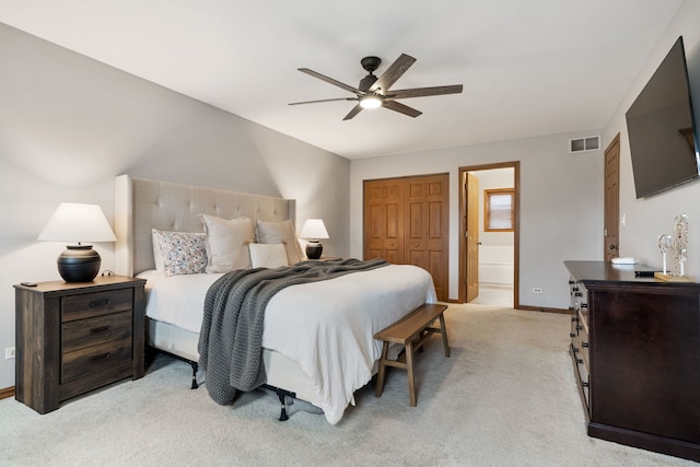 bedroom with light carpet, a closet, ensuite bath, and ceiling fan