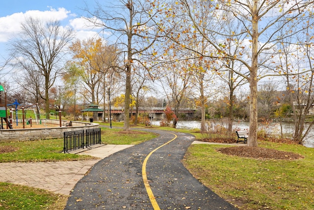 view of property's community with a playground, a yard, and a water view