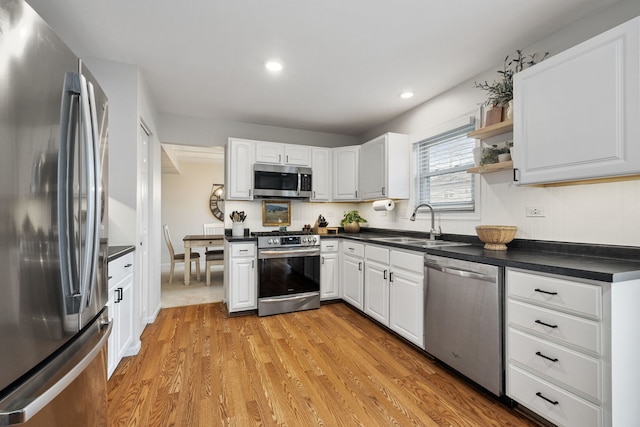 kitchen featuring appliances with stainless steel finishes, light hardwood / wood-style floors, white cabinetry, and sink