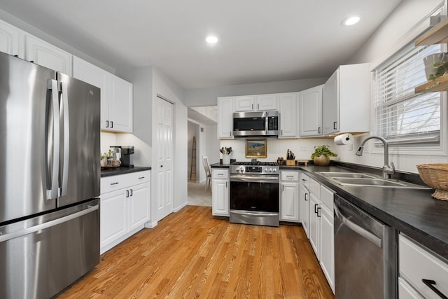 kitchen featuring white cabinets, sink, light wood-type flooring, and stainless steel appliances