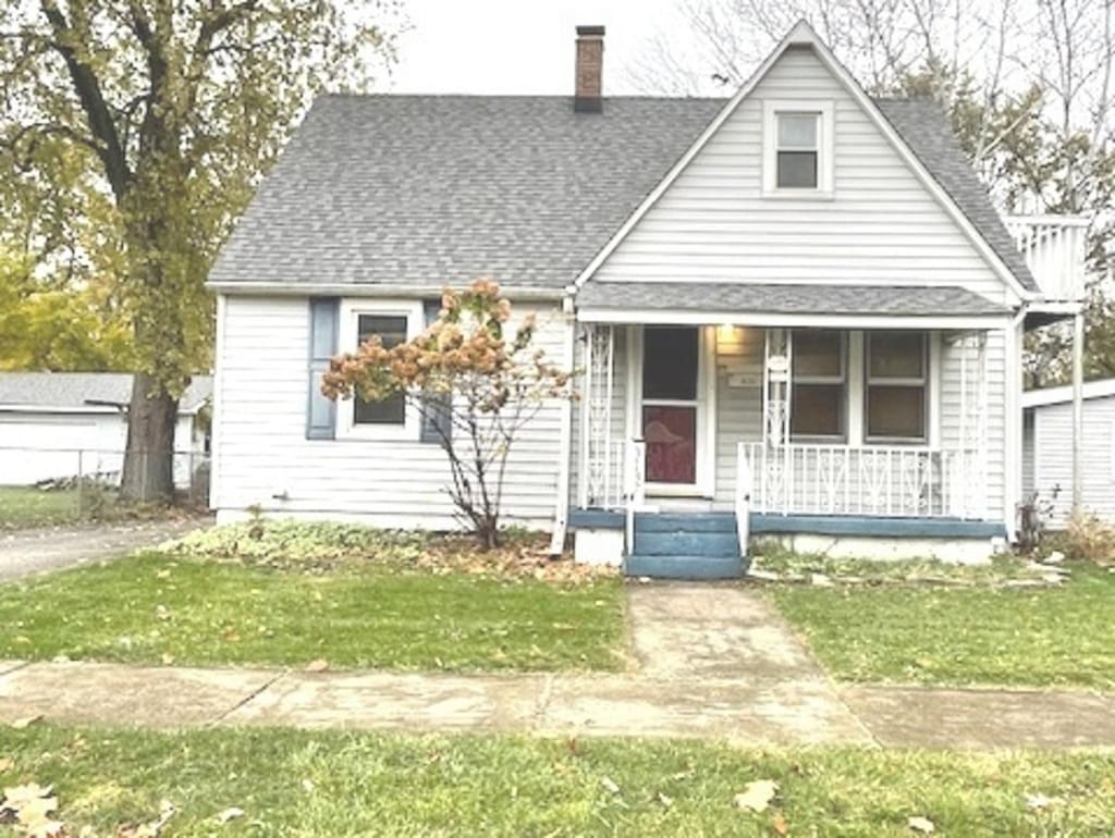 bungalow-style home with covered porch, a chimney, a shingled roof, and a front yard