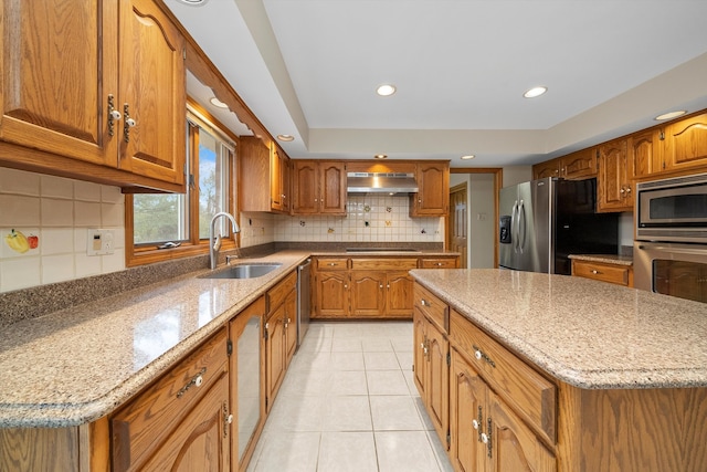 kitchen with stainless steel appliances, light tile patterned flooring, sink, light stone countertops, and a center island