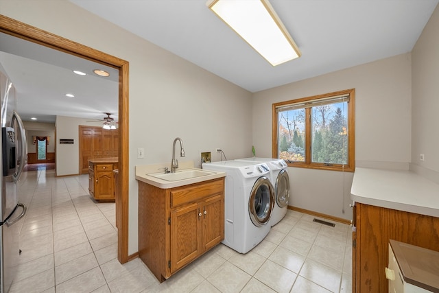 washroom with light tile patterned floors, cabinets, sink, washing machine and dryer, and ceiling fan