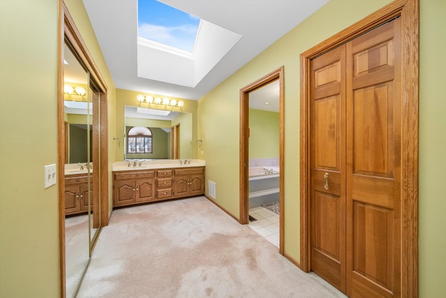 bathroom featuring a skylight, vanity, tile patterned floors, and a bathing tub