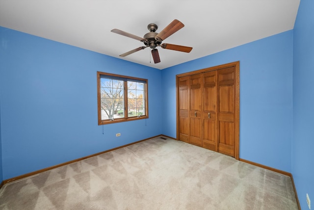 unfurnished bedroom with ceiling fan, light carpet, and a closet