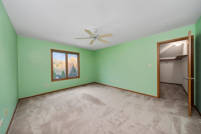 unfurnished bedroom with ceiling fan, light carpet, a closet, and a spacious closet