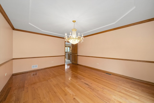 empty room featuring light wood-type flooring, a notable chandelier, and crown molding