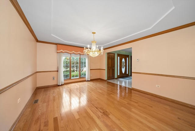 spare room featuring a chandelier, hardwood / wood-style floors, ornamental molding, and a raised ceiling