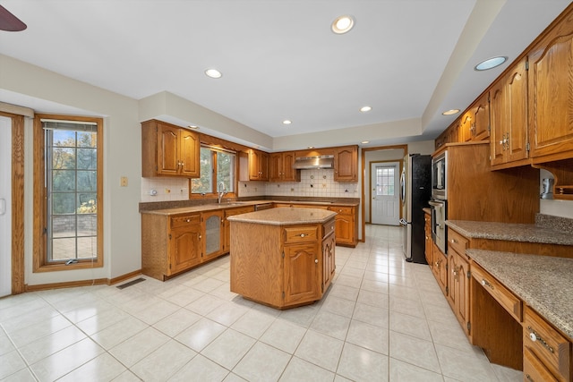 kitchen featuring sink, appliances with stainless steel finishes, backsplash, ventilation hood, and a center island