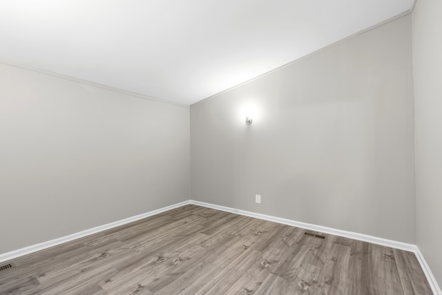 spare room with crown molding and light wood-type flooring