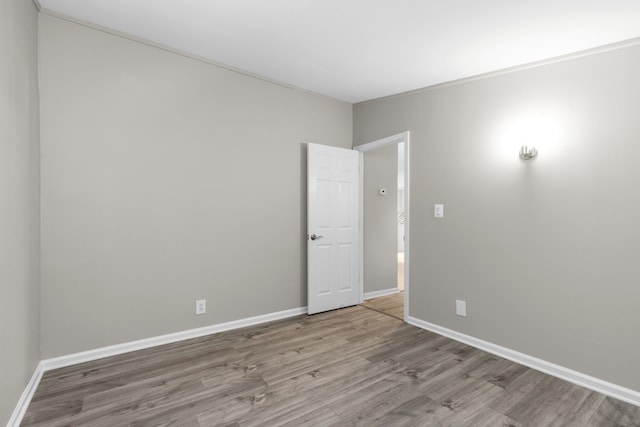 spare room featuring ornamental molding and light hardwood / wood-style flooring