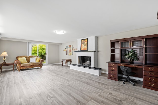 office area with light hardwood / wood-style flooring and a brick fireplace