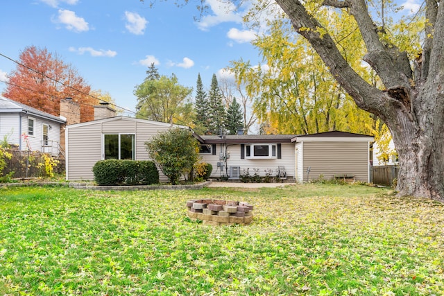 rear view of property with an outdoor fire pit and a lawn