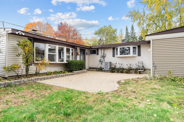 back of property with a yard, central air condition unit, and a patio area