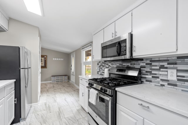 kitchen featuring lofted ceiling, white cabinetry, and stainless steel appliances