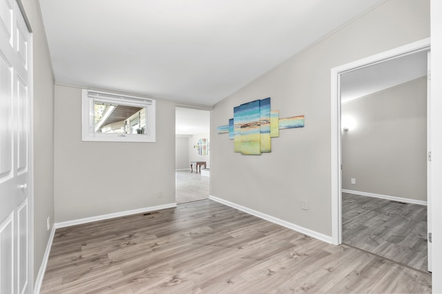 spare room with light hardwood / wood-style floors and vaulted ceiling