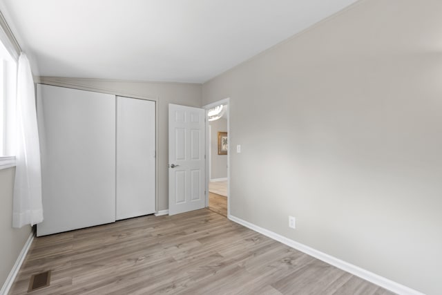 unfurnished bedroom featuring a closet, vaulted ceiling, and light hardwood / wood-style flooring