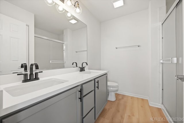 bathroom with vanity, hardwood / wood-style floors, toilet, and an enclosed shower