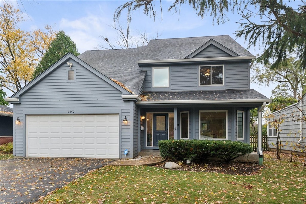 view of front of house with covered porch, a front yard, and a garage