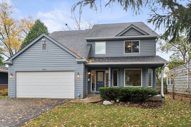 view of front of house with covered porch, a front yard, and a garage